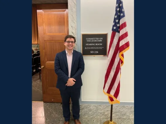 Man standing next to an American Flag smiling.