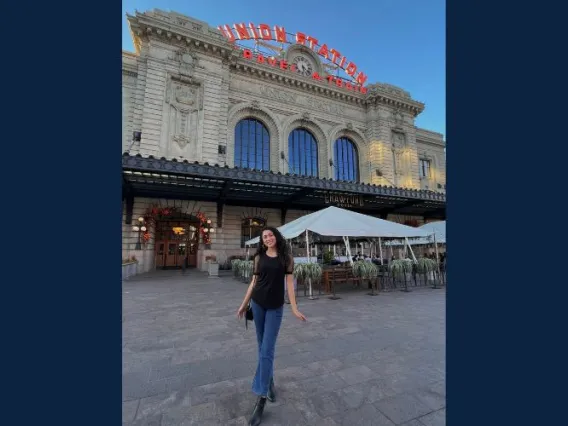 Woman with brown hair smiling standing in front of the union station.