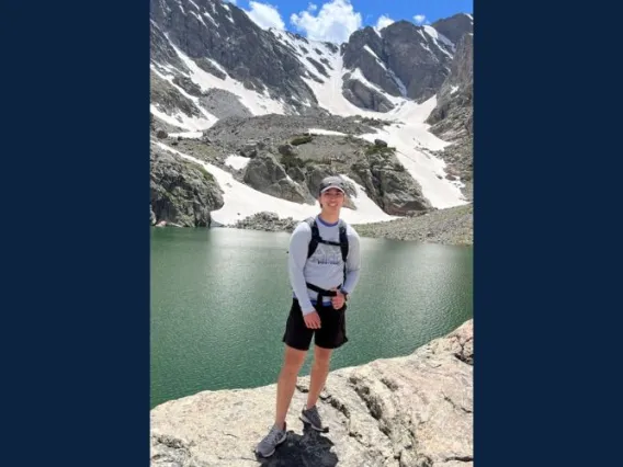 Man smiling in front of a snowy mountain.