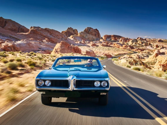 Man driving car desert road