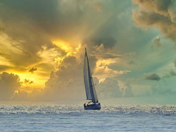 Ship sails into sunset and storm