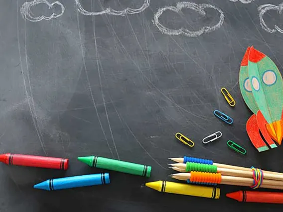 Chalkboard with crayons and clouds drawn in white chalk