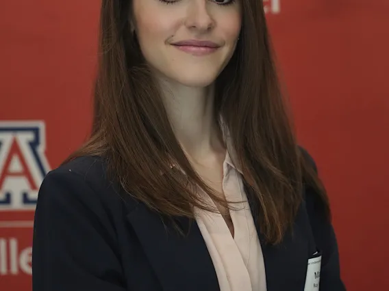 woman with long dark hair standing in front of a red back ground