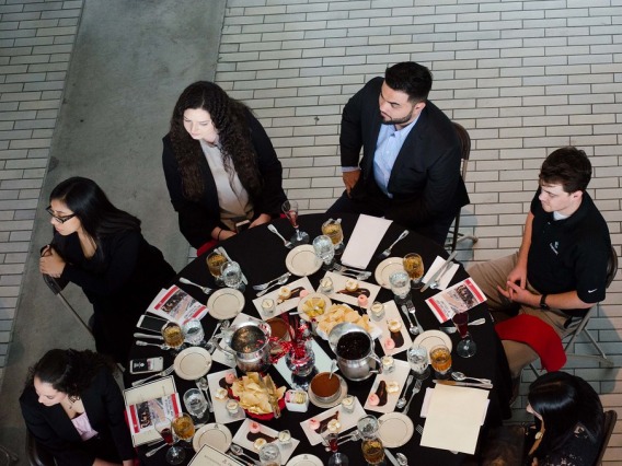 Image from above of people sitting around a round table with food and other items