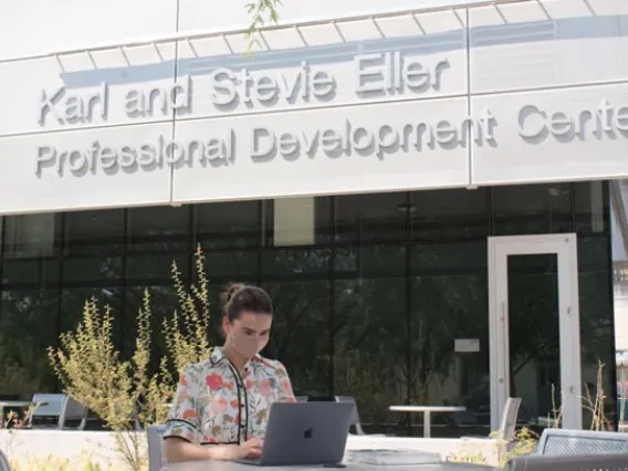 student sitting along outside on laptop