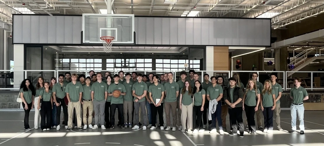 Students wearing green polos in front of a basketball hoop