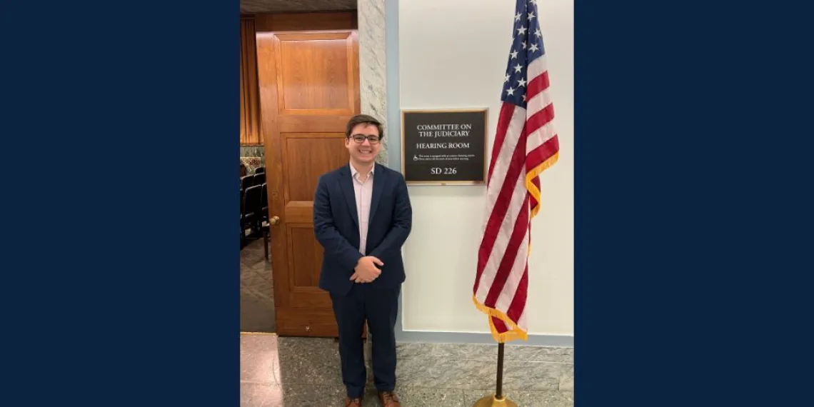 Man standing next to an American Flag smiling.