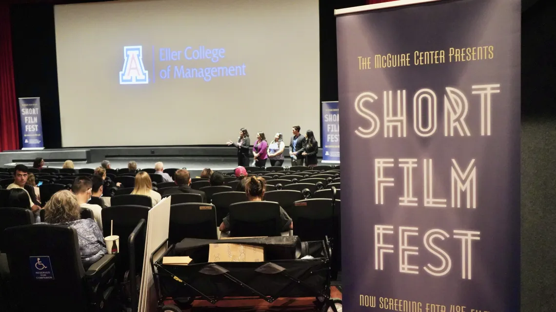 A cinema screen in the background with the audience and a banner for the Short Film Festival in the foreground.