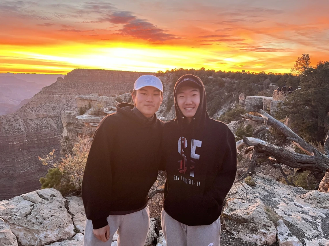 Two students in front of the sunrise at the Grand Canyon