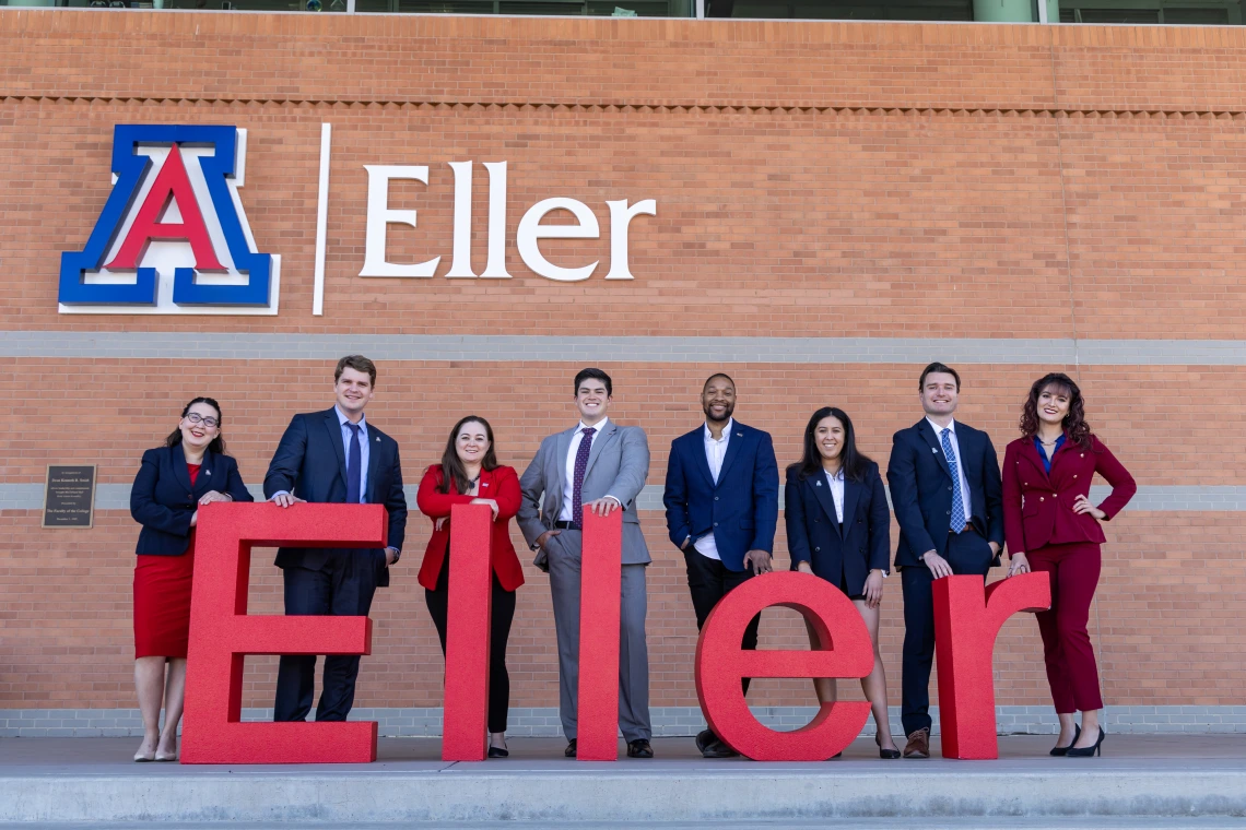 Students under new building sign with ELLER red letters