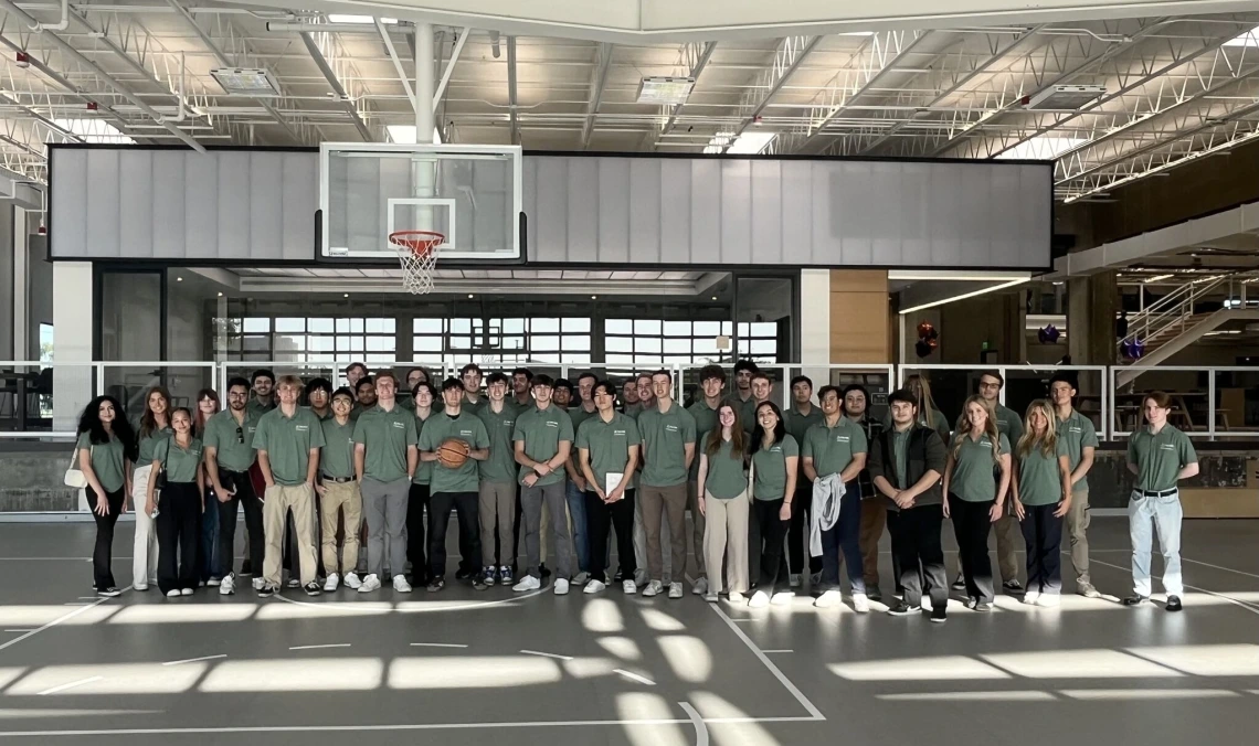 Students wearing green polos in front of a basketball hoop