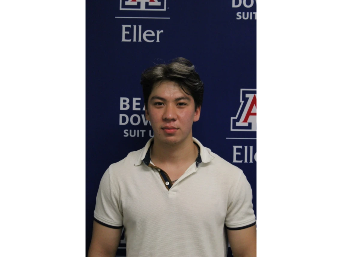 Jakhongir in white collared shirt in front of Eller photo backdrop