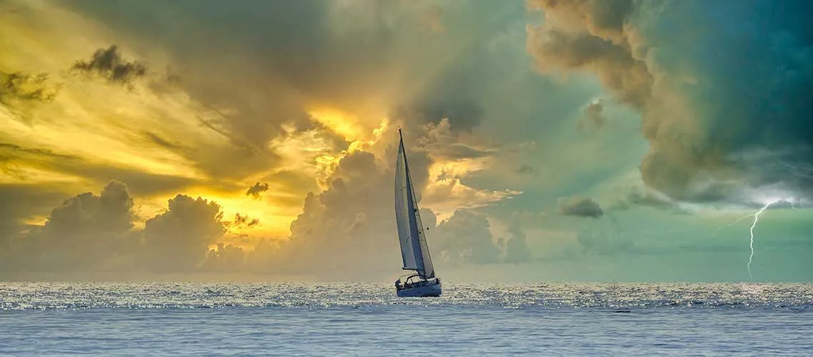 Ship sails into sunset and storm