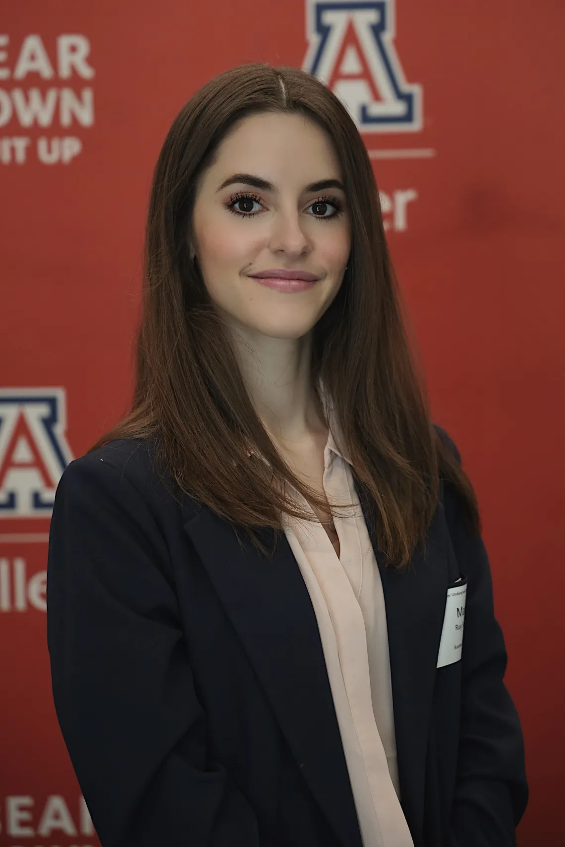 woman with long dark hair standing in front of a red back ground