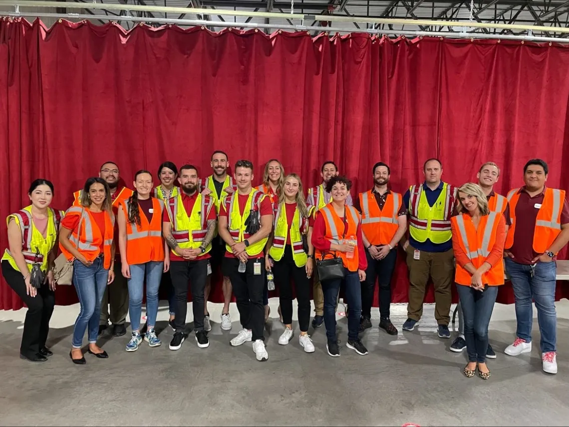 group of people in neon work vests standing in front of red curtain