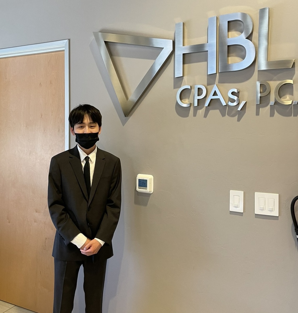 Simon Jeon standing in front of HBL CPAs P.C. metal signage.
