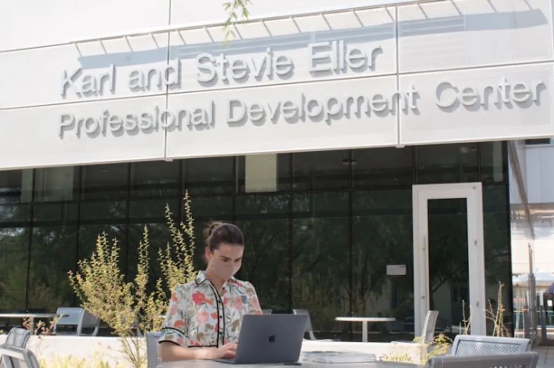 student sitting along outside on laptop