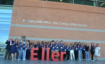 Group picture outside building red letter spell ELLER