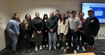 A group of people in a classroom with a large screen in the background