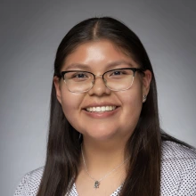 Student wearing glasses and a shirt with polka dots and smiling