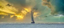 Ship sails into sunset and storm