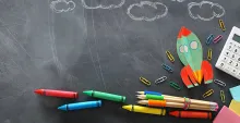 Chalkboard with crayons and clouds drawn in white chalk