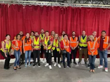 group of people in neon work vests standing in front of red curtain